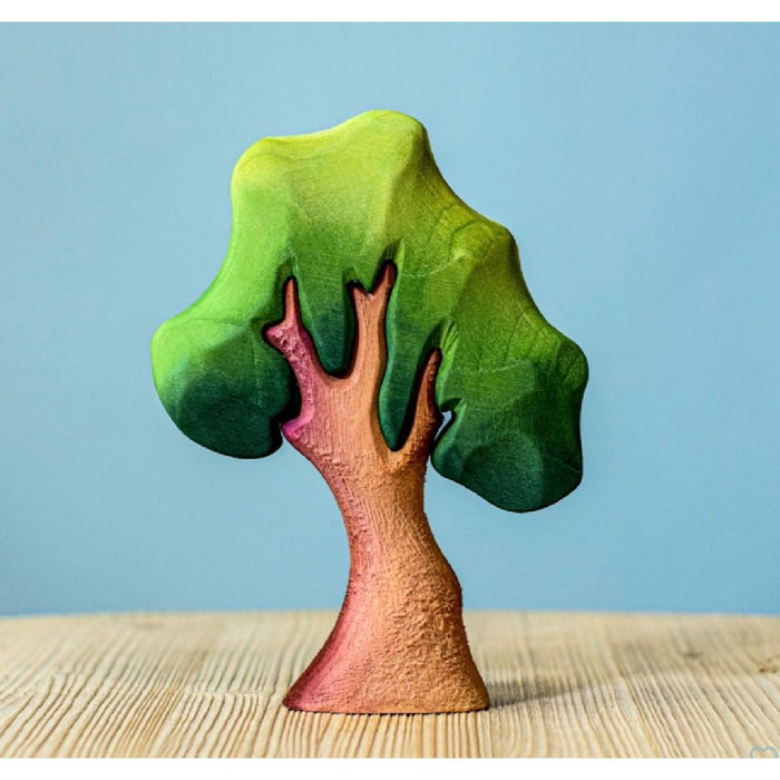 Small tree figurine with green leaves on a wooden surface and blue background