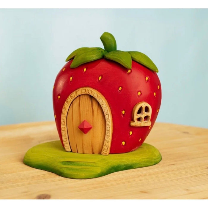 Strawberry-shaped house with a wooden door and window on a light blue background