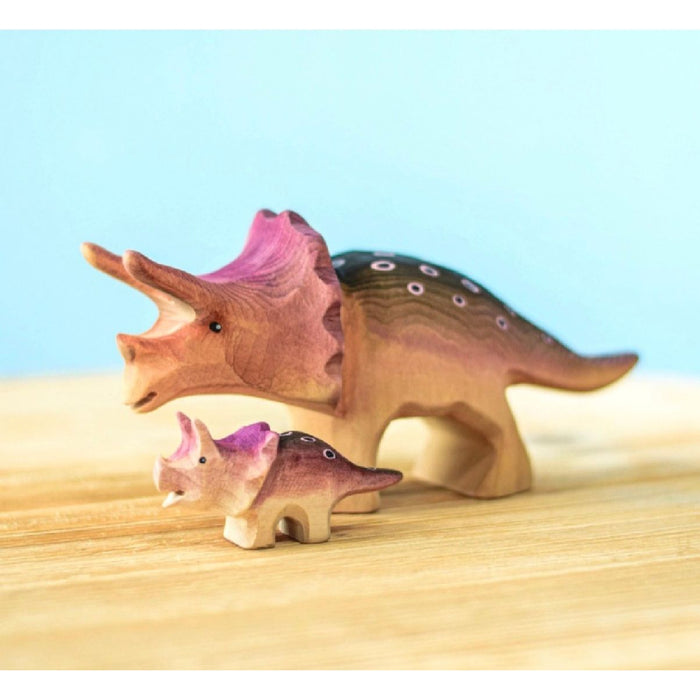 Wooden triceratops dinosaur toys on a wooden surface with a light blue background