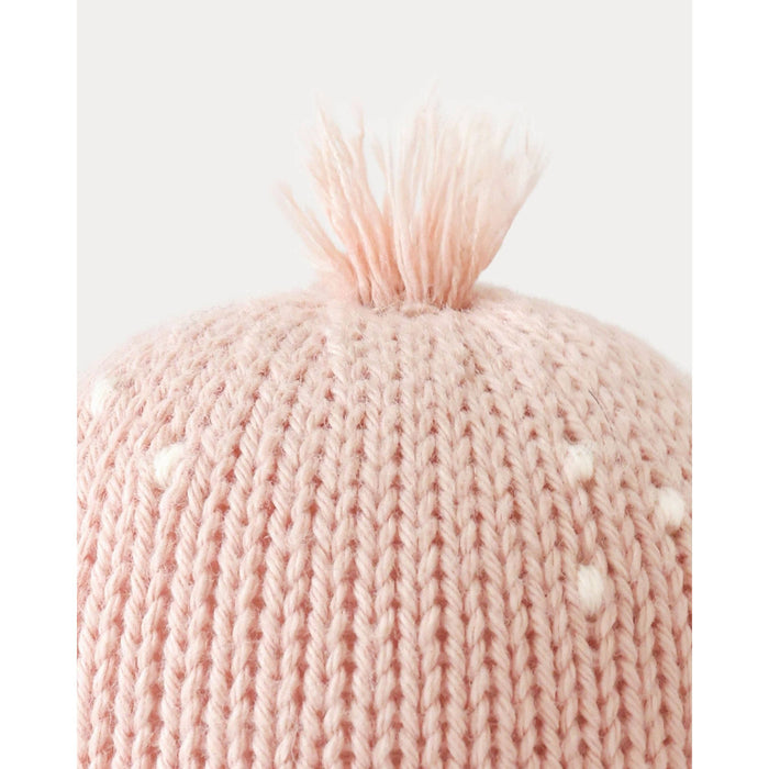 Close-up of a pink knitted beanie with a fluffy pom-pom