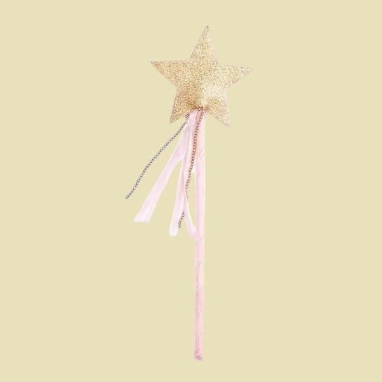 A children's toy magic wand featuring a glittery gold star topper with pink and silver tinsel accents on a long pink handle, isolated on a white background.