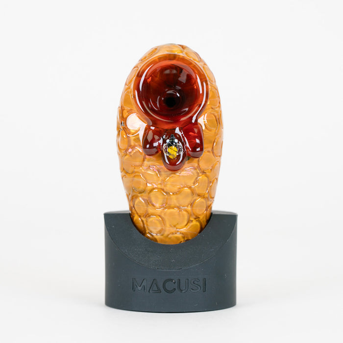 Beehive Macusi glass pipe with small bee figurine in honey on a white background